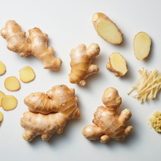 Fresh ginger roots with sliced, grated, and julienned ginger pieces arranged on a clean light background.