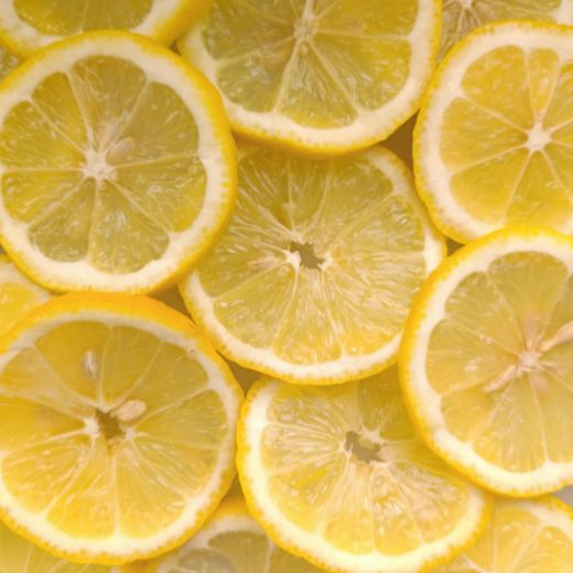 Close-up image of fresh lemon slices layered together, showing bright yellow citrus texture and natural juice.