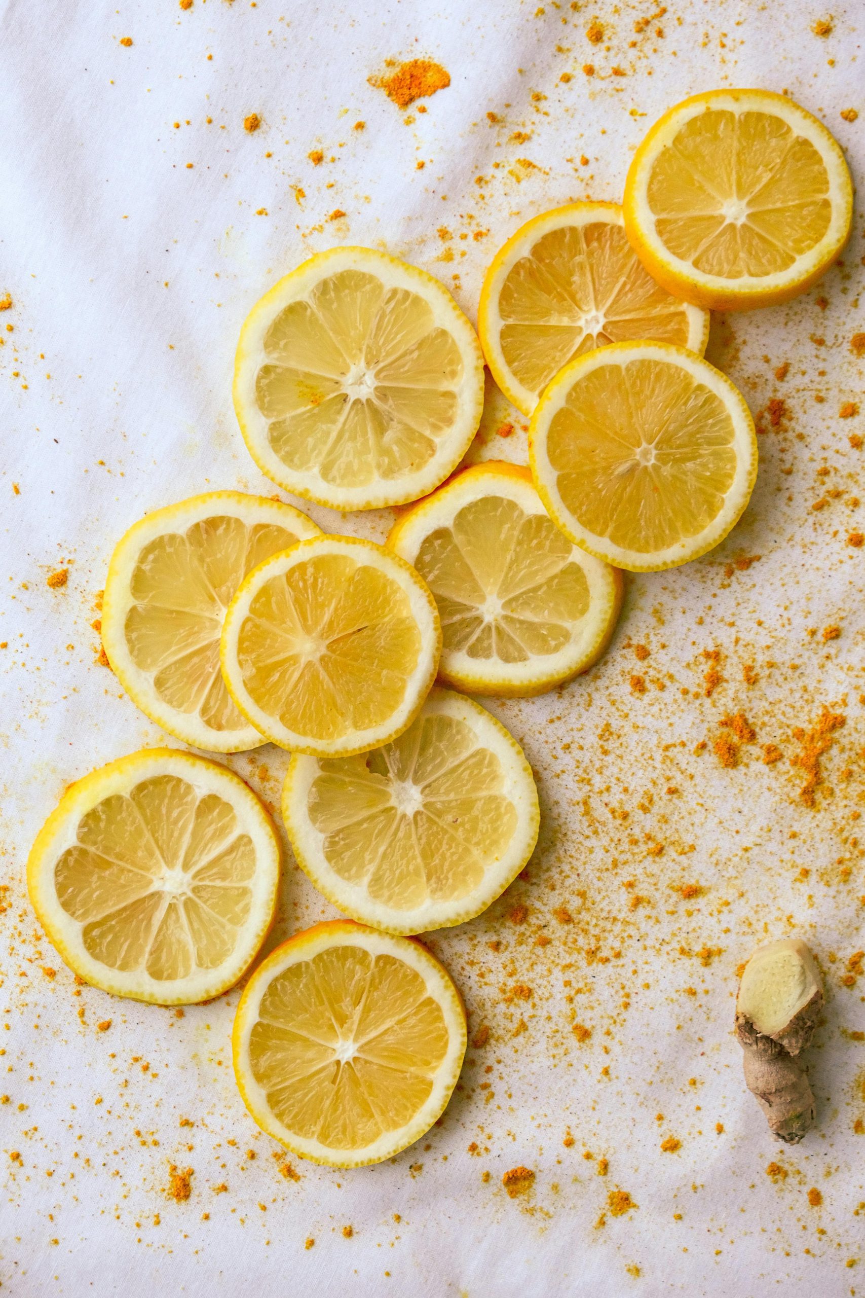 Lemon Slices with Turmeric and Ginger Fresh lemon slices arranged on a light surface with turmeric powder and a small piece of ginger.